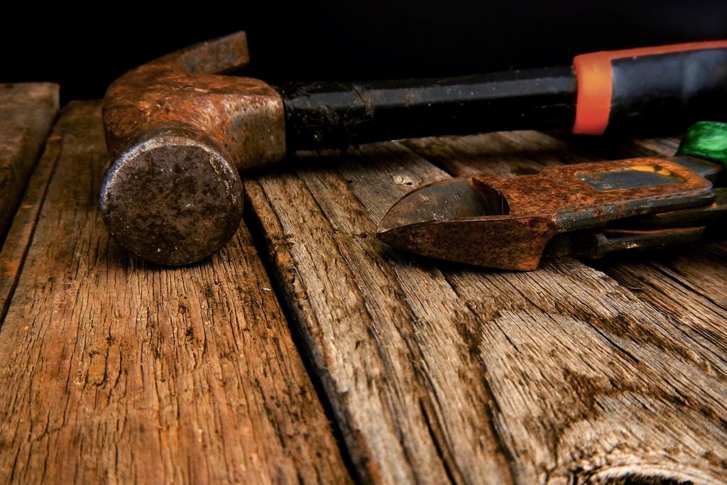 Hammer and pliers resting on a weathered wooden workbench