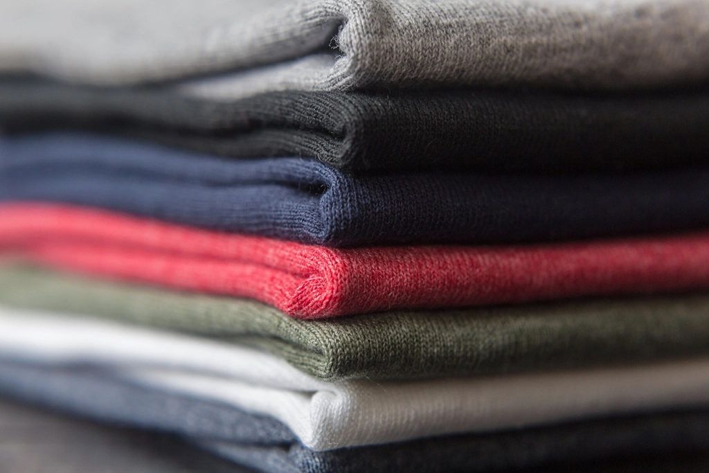 Stack of folded blank T-shirts in gray, black, navy, red, green and white