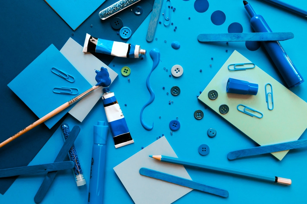 Blue craft supplies, paper and tools laid out on a work surface