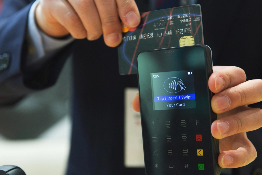 A card being held next to a handheld card payment reader