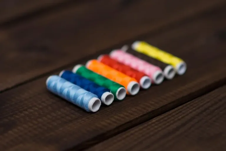 Row of colorful thread spools on a dark wooden table