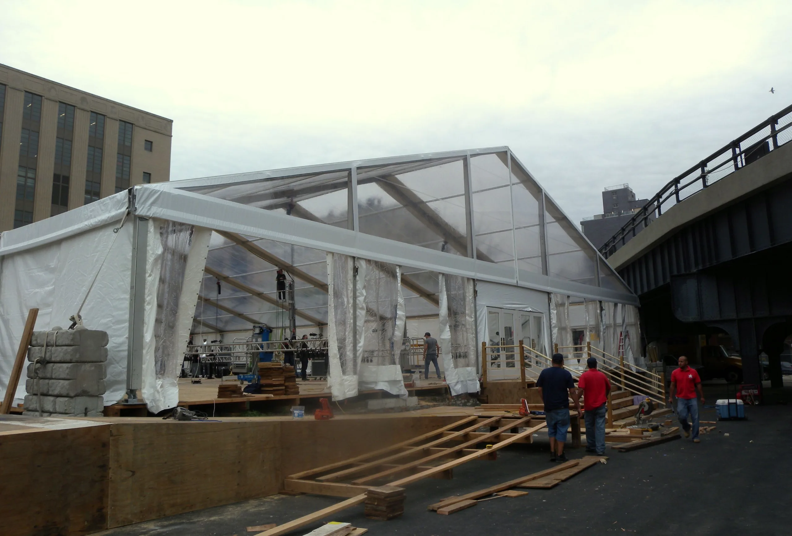 Crew assembling a large white frame event tent outdoors