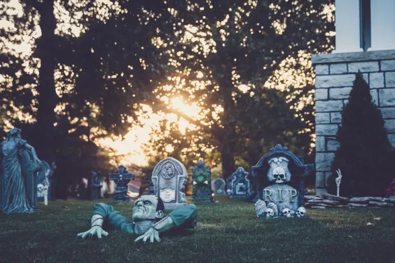 Halloween yard decorations with gravestones and figures at dusk
