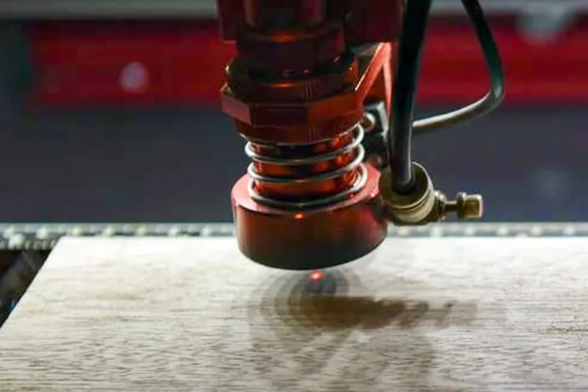 Laser engraver head etching a wooden board