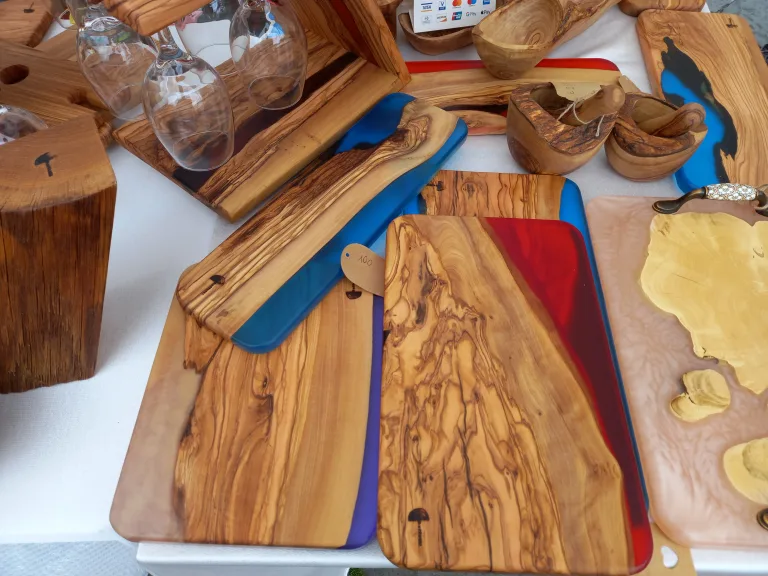 Olive wood serving boards with blue and red epoxy resin inlays displayed on a market table