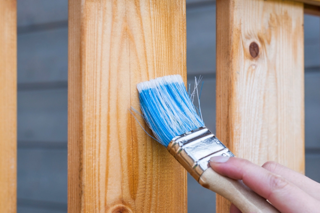Paintbrush applying finish to a wooden board