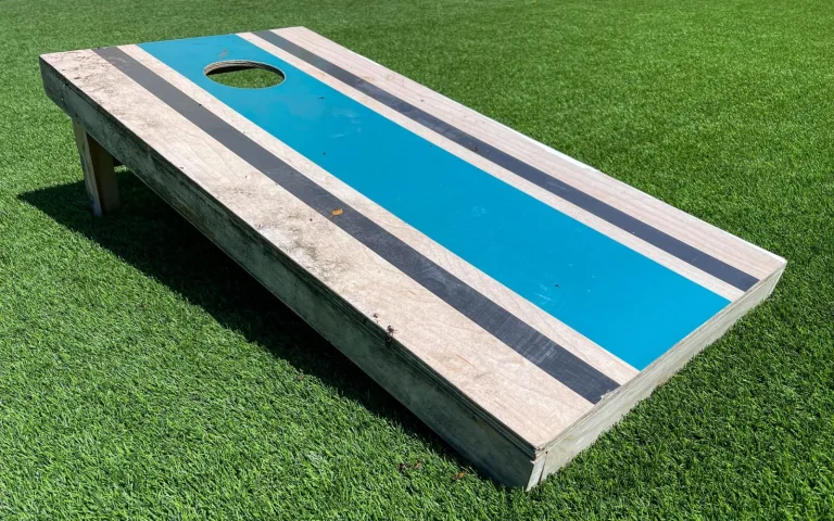 A painted wooden cornhole board on green grass