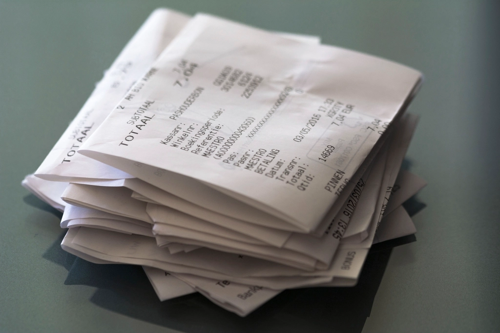 A small pile of folded paper sales receipts on a table