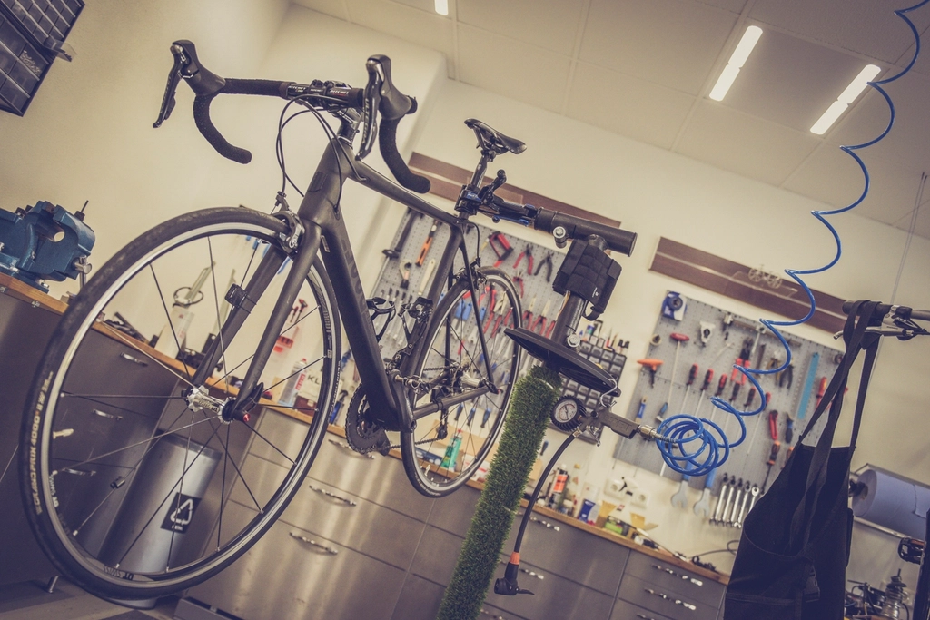 Road bike on a repair stand in a tidy workshop with tools hanging on a pegboard wall