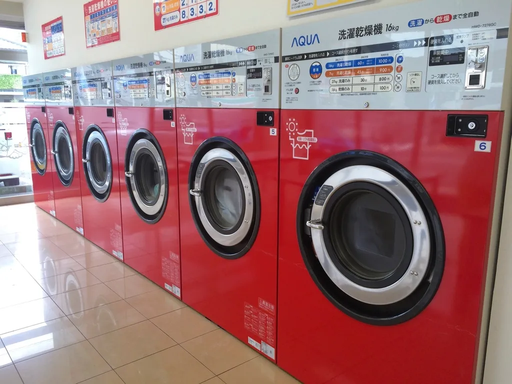 Row of red front-loading clothes dryers in a laundry room