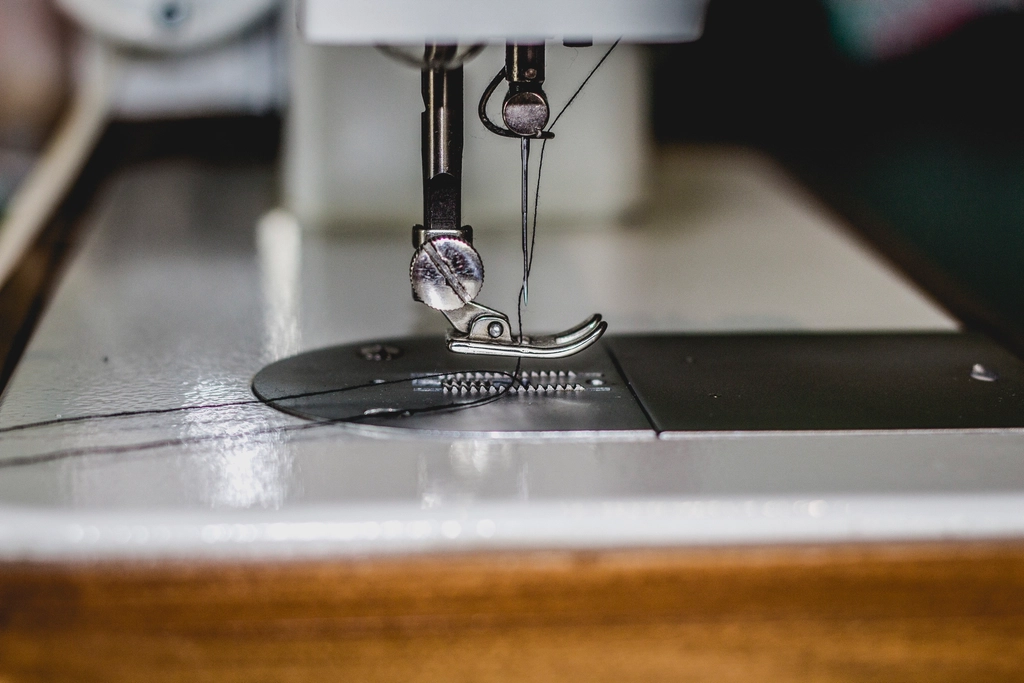 Close-up of a sewing machine needle and presser foot over the throat plate