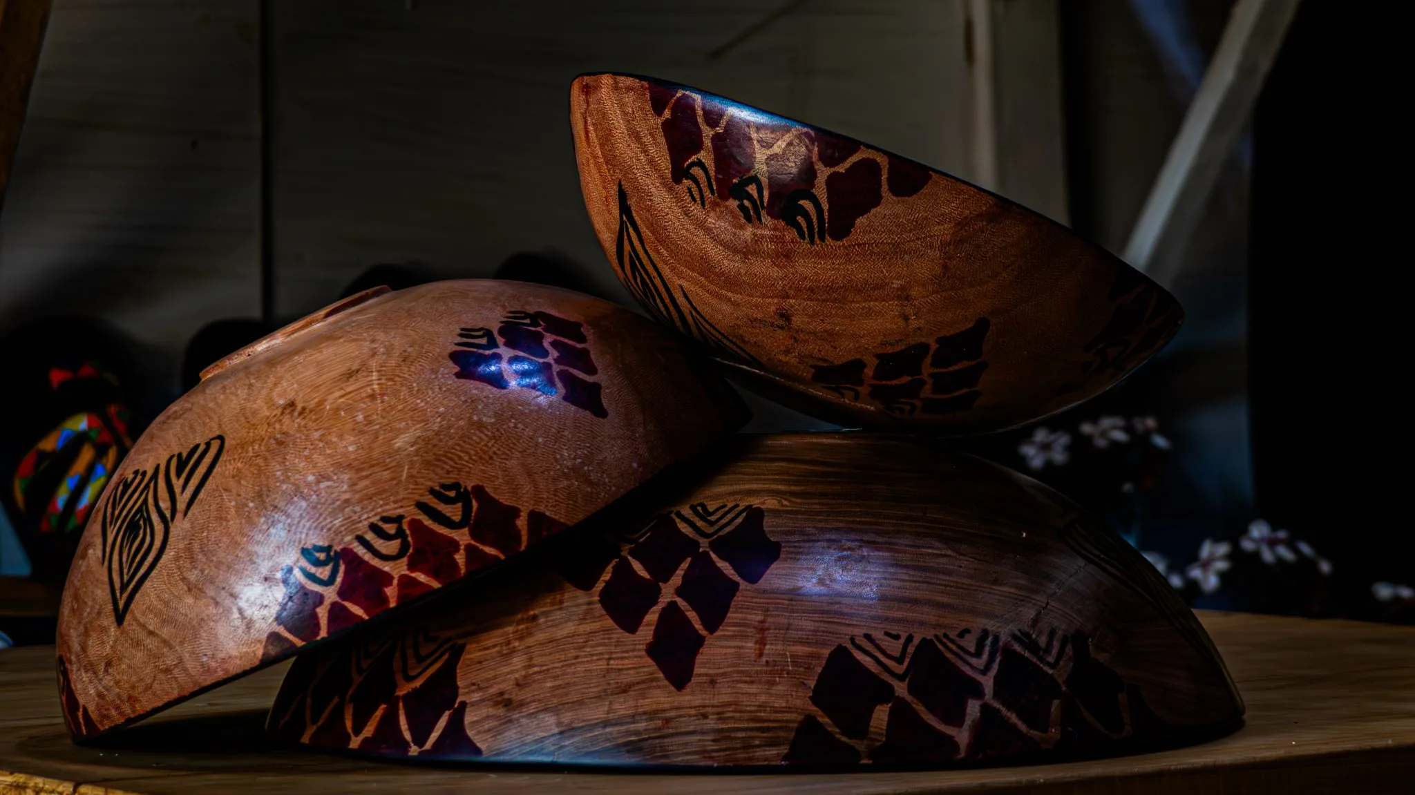 Stacked handmade wooden bowls with carved patterns on a shelf
