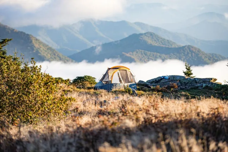 Tent pitched on a grassy ridge overlooking misty mountains
