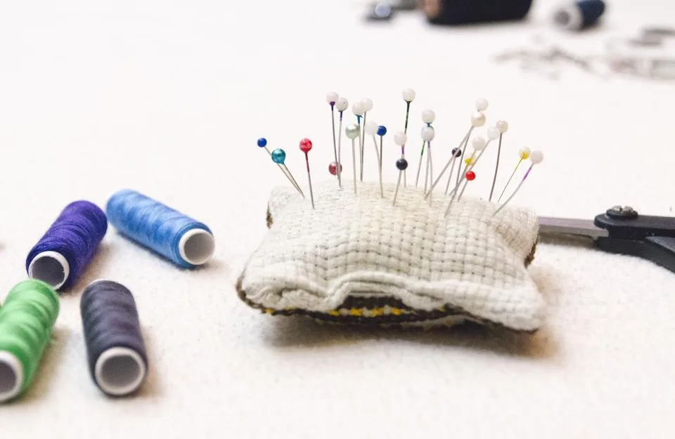 Spools of thread and a pincushion on a white craft table