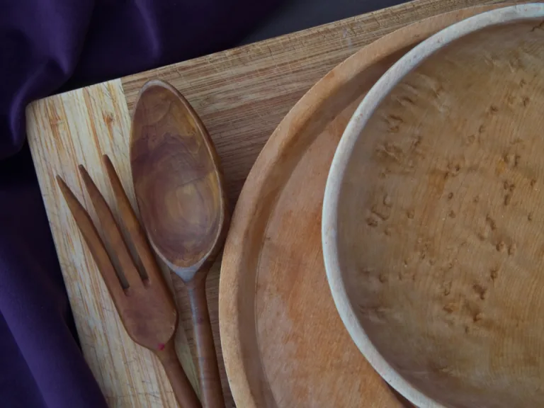 Handmade wooden bowl, plate, spoon and fork on a wooden board