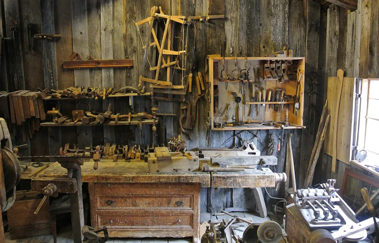 Rustic woodworking workshop with hand tools hanging on a plank wall above a wooden workbench