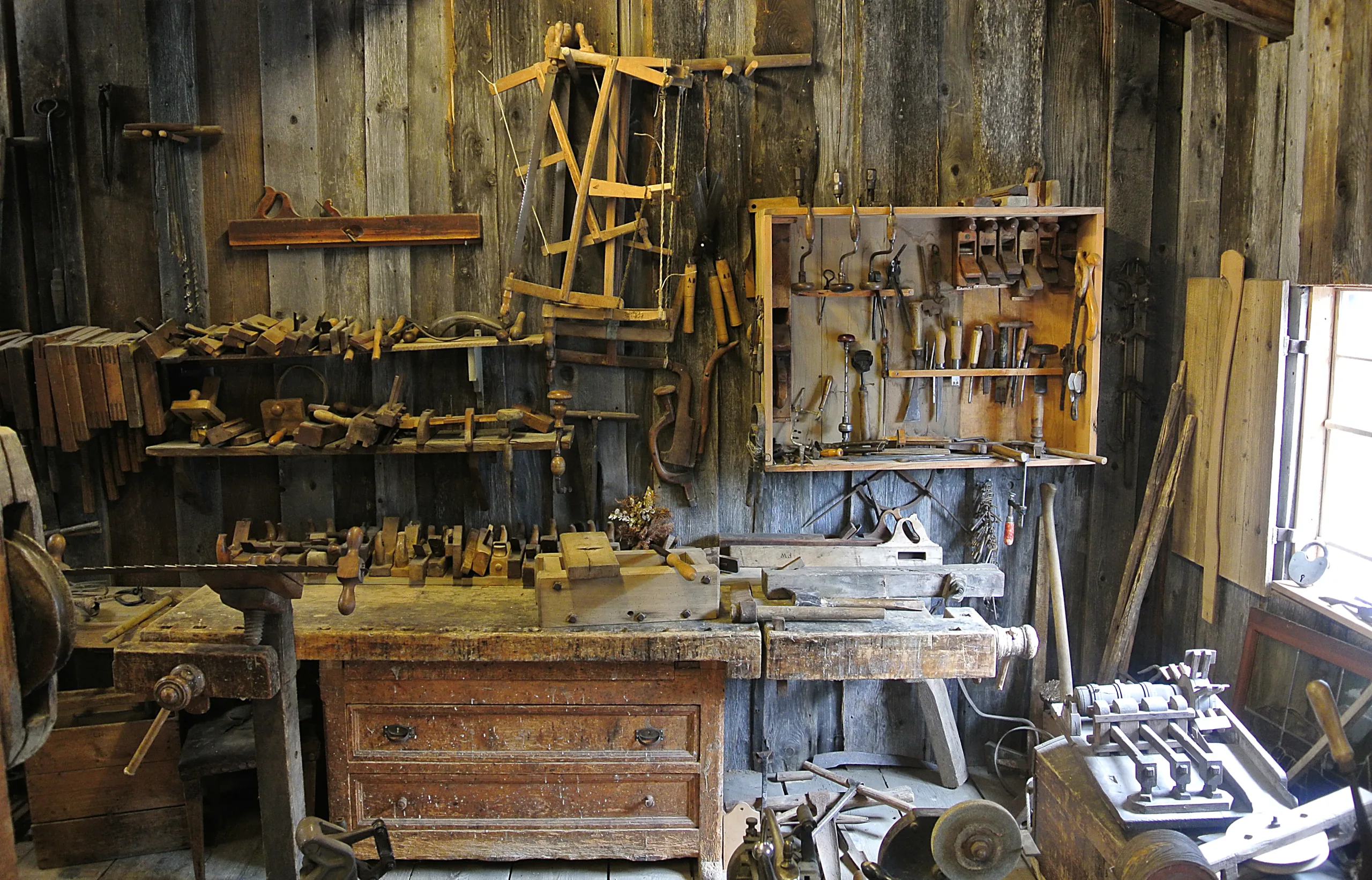 Rustic woodworking workshop with hand tools hanging on a plank wall above a wooden workbench